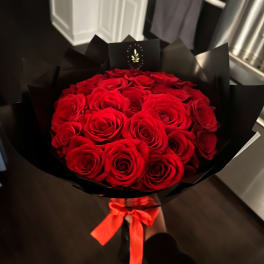 Bouquet of red roses wrapped in black paper with a red ribbon