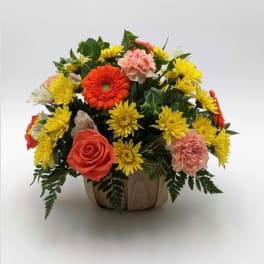 Mixed bouquet in a wooden container with orange, yellow, and pink flowers