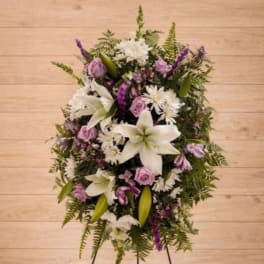 Standing floral wreath with white lilies, lavender roses, and purple accents
