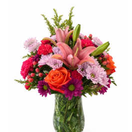 Mixed bouquet with pink lilies, roses, and chrysanthemums in a glass vase