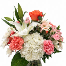 Mixed bouquet of lilies, roses, hydrangea, and carnations in a glass vase