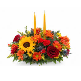 Bright floral centerpiece with two tall yellow candles