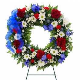 Circular floral wreath with red, white, and blue flowers on a stand
