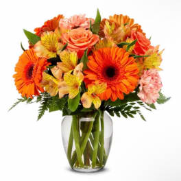Bouquet of orange and pink flowers in a clear glass vase