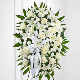 White floral standing spray with roses and lilies on an easel