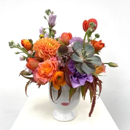 Colorful mixed bouquet in a white pedestal vase with a succulent accent