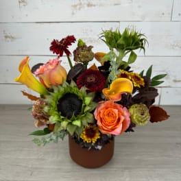 Mixed bouquet with sunflowers, roses, calla lilies, and chrysanthemums in a brown vase
