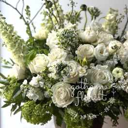 White roses and ranunculus arranged in a dark vase