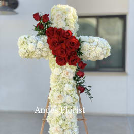 Cross-shaped floral tribute with red and white roses on an easel