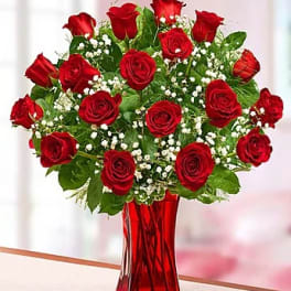 Red roses arranged in a tall red glass vase