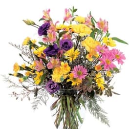 Mixed bouquet of yellow, pink, and purple flowers in a clear glass vase