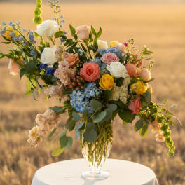 Mixed roses and blue flowers in a clear glass vase on a round table