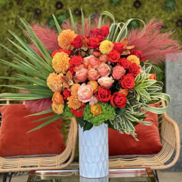 Bright bouquet of red, pink, and orange flowers in a white vase