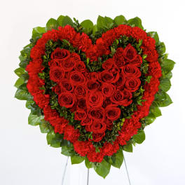 Heart-shaped red rose and carnation arrangement on a stand