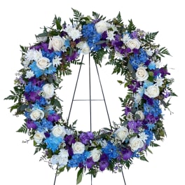 Large floral wreath with white roses, blue hydrangeas, and purple flowers