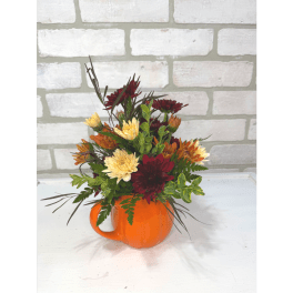 Mixed autumn flowers arranged in an orange mug