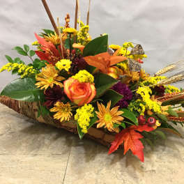 Autumn floral arrangement in a woven basket with orange roses and yellow blooms
