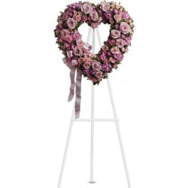 Heart-shaped pink rose wreath on a white easel with ribbon