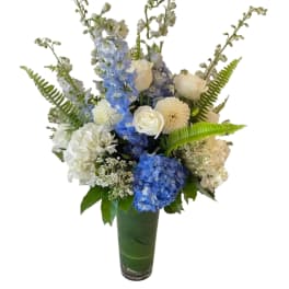 Blue and white floral arrangement in a tall green vase