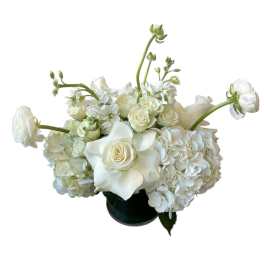 White floral arrangement in a dark vase with roses and hydrangeas