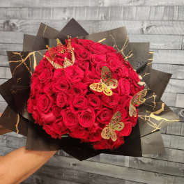 Large bouquet of red roses wrapped in black paper with gold accents