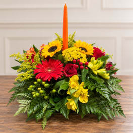 Colorful floral centerpiece with a tall orange taper candle