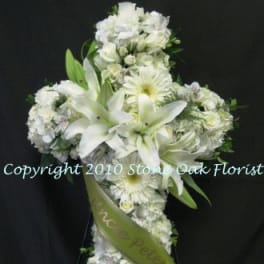 White floral cross arrangement with lilies and daisies on a black background