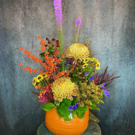 Colorful autumn floral arrangement in a pumpkin-shaped container