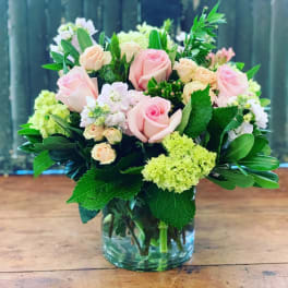 Pink and peach roses in a glass vase with green and white flowers