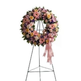 Floral wreath on a metal easel with a pink ribbon