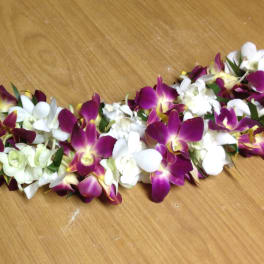 Purple and white orchid lei laid on a wooden surface