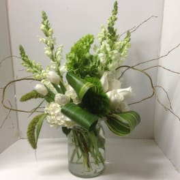 White flowers and green blooms arranged in a glass vase