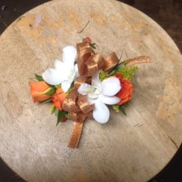 Small floral corsage with white and orange blooms and a copper ribbon