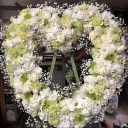 Heart-shaped floral wreath of white and pale green flowers on an easel