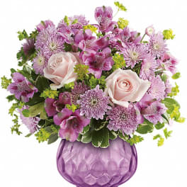 Pink roses and purple flowers arranged in a purple glass vase