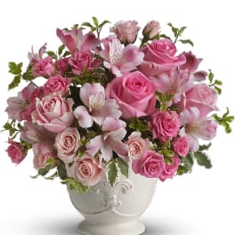Pink roses and alstroemeria arranged in a white ceramic footed vase