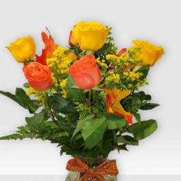 Orange and yellow roses in a glass vase with an orange ribbon