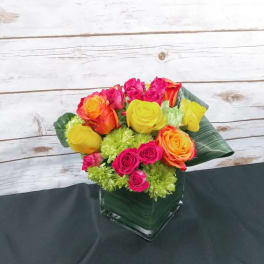 Bright mixed rose bouquet in a square glass vase