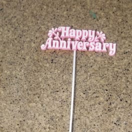 Pink "Happy Anniversary" cake topper on a white stick