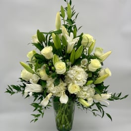 White roses and lilies arranged in a clear glass vase
