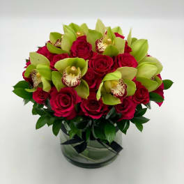 Bouquet of red roses and green orchids in a glass vase