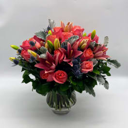 Pink lilies and roses arranged in a clear glass vase