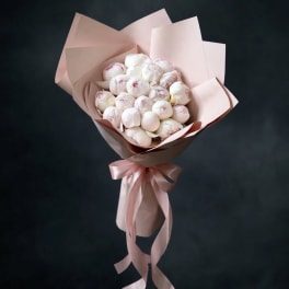Bouquet of pale pink and white peonies wrapped in blush paper with a ribbon