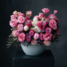 Pink roses and carnations arranged in a white vase
