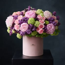 Pink and purple floral arrangement in a blush cylindrical box