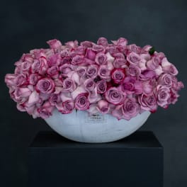 Pink and lavender roses arranged in a white bowl vase