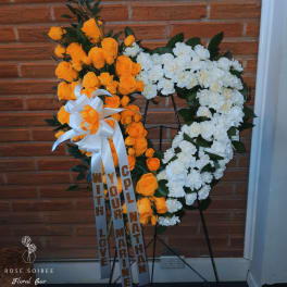 Heart-shaped floral wreath with orange roses and white flowers on a stand