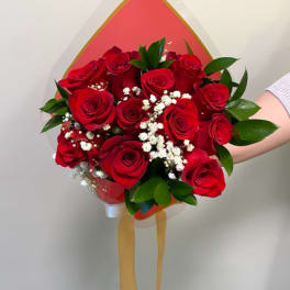 Bouquet of red roses with white baby's breath and green leaves in wrapping