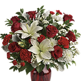 Red roses and white lilies arranged in a red glass vase
