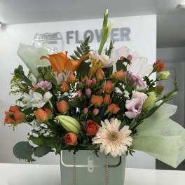 Mixed bouquet in a mint gift box with orange and white blooms